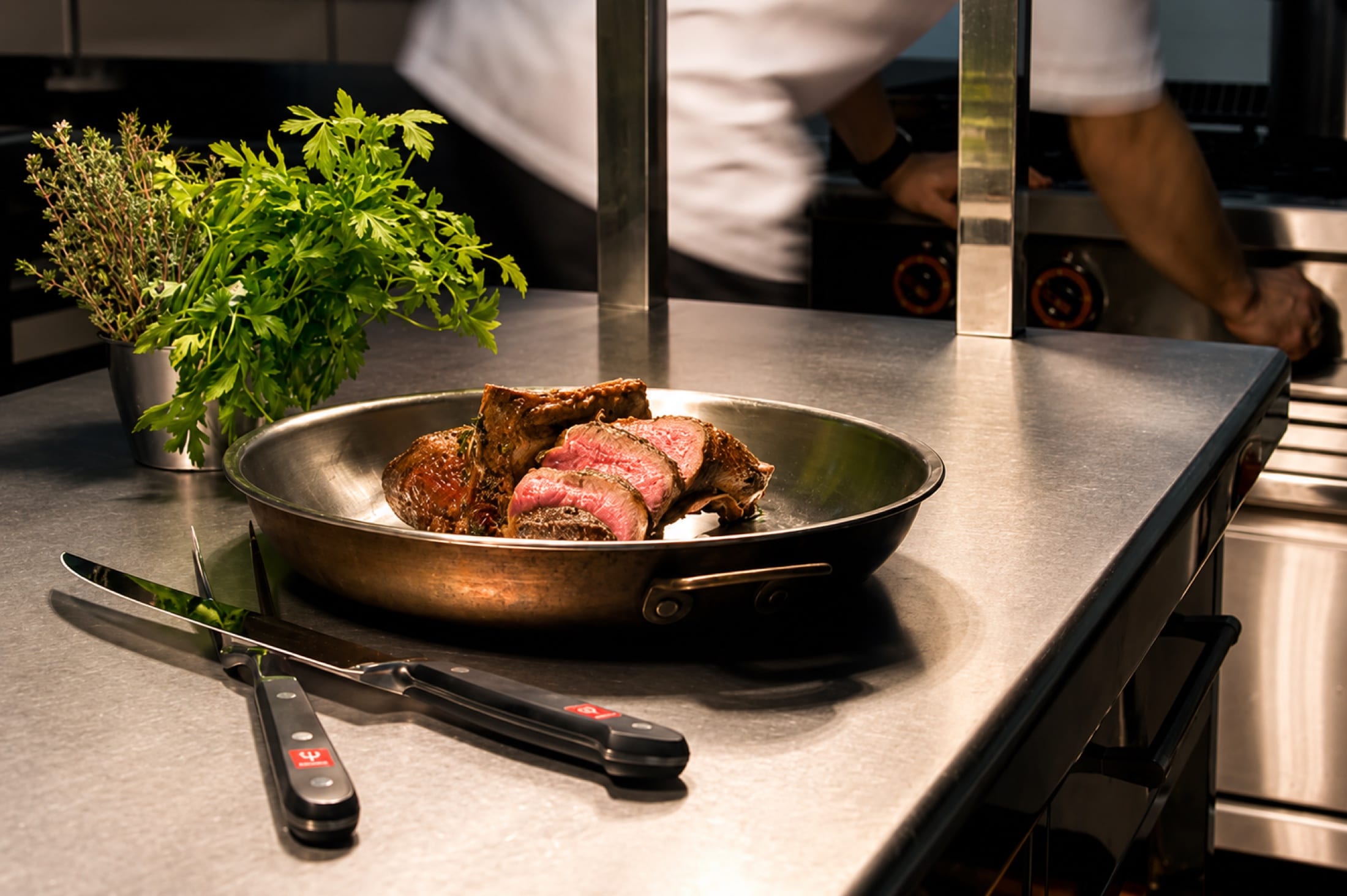 Rinderfilet in der Pfanne auf dem Küchentresen, dahinter der Küchenchef